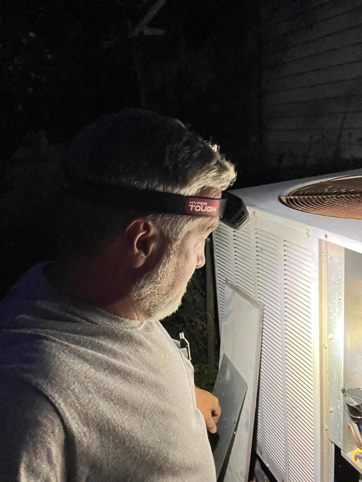 Technician working on HVAC at night